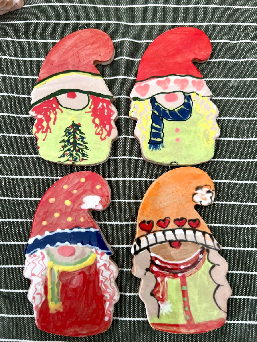 Four hand-painted ceramic gnome ornaments in red and orange hats